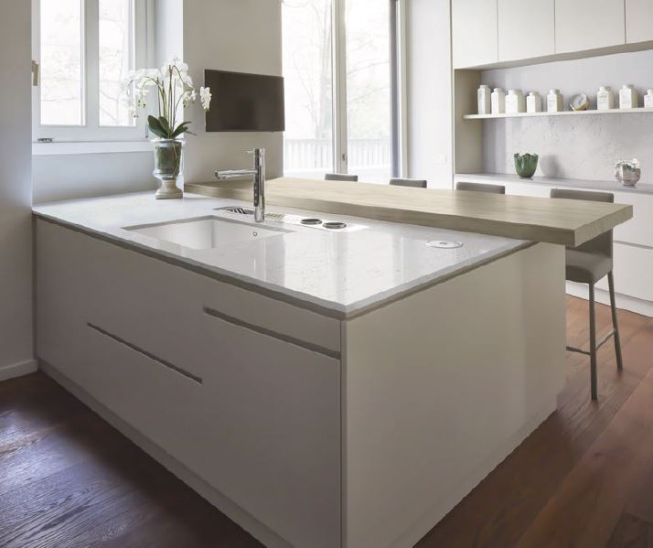 White kitchen island with a Corian worktop in white and a wooden breakfast bar
