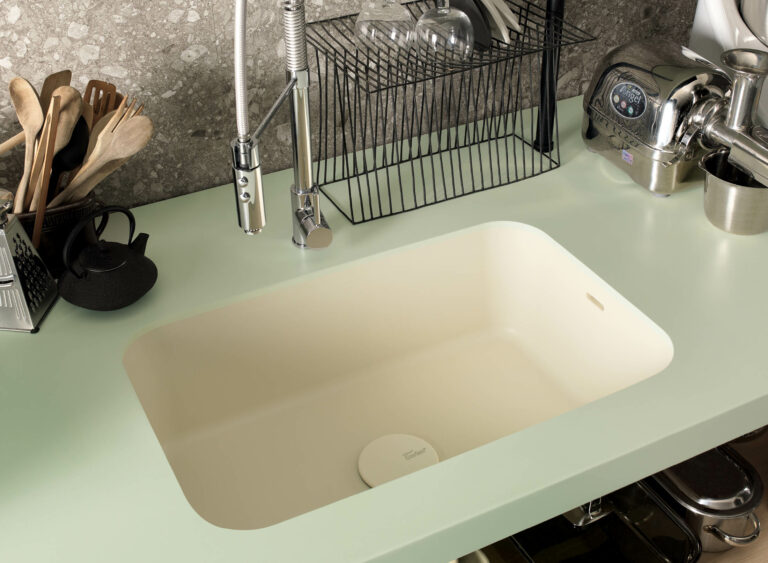 Light green Corian kitchen worktop with kitchen sink options of a white integrated Corian sink